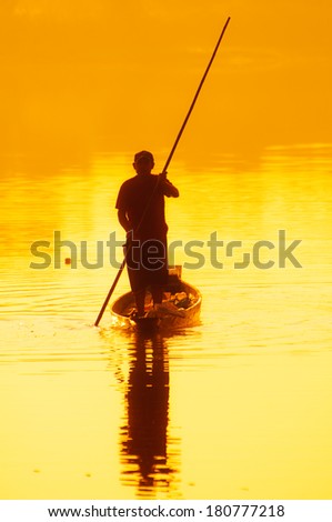Silhouette of fisherman with yellow and orange sunshine in the background.