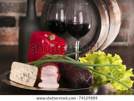 Still life with wine and vegetables, cheese and ham. Against the backdrop of a brick wall.