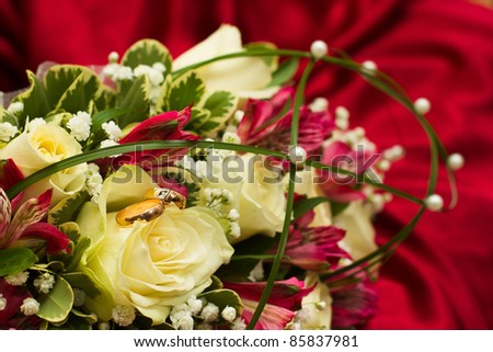 stock photo Gold wedding rings on the wedding bouquet of roses and orchids