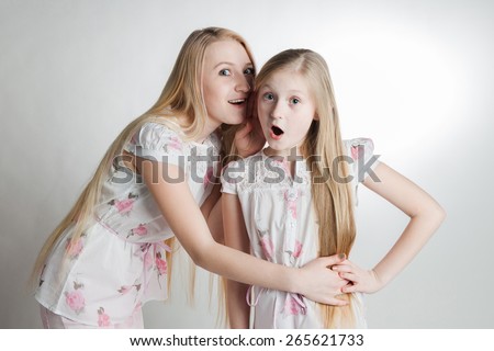 two blonde's girls, the girl whispers on an ear to other girl