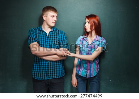 Portrait Of Beautiful Young Couple Over Dark Green Wall. Hard times in relationships. Man and woman try to agree. Reconciliation. Red-haired woman and blonde man in check shirts.