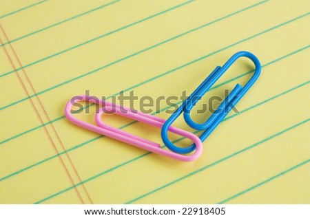 Pink (female) and blue (male) paper clips connected on a legal pad of paper