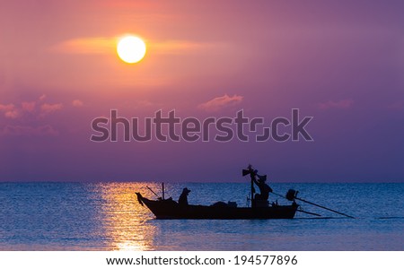 Silhouette image of Fishermen in fishing boat at sunset