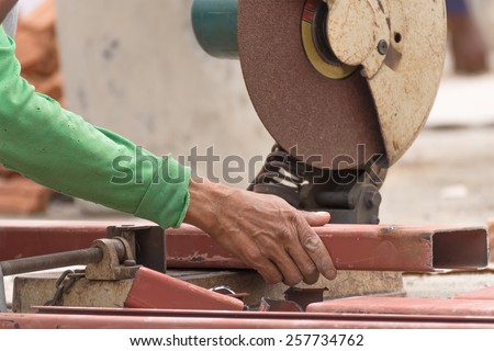 Worker cutting metal with grinder in construction site. Sparks while grinding iron