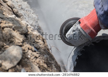 Plumbers cutting concrete water pipes by metal grinding