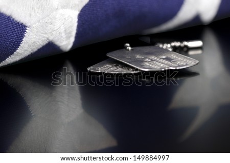 Dog tags or ID tags, once worn by a military veteran with a folded US flag