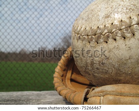Well used softball and catcher\'s mitt with shallow depth of field