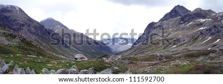 The Julier Pass is a mountain pass in the canton of GraubÃ?Â¼nden in Switzerland; barren high mountain landscape, sky overcast; panoramic image/ Panorama at Julier Pass in Switzerland