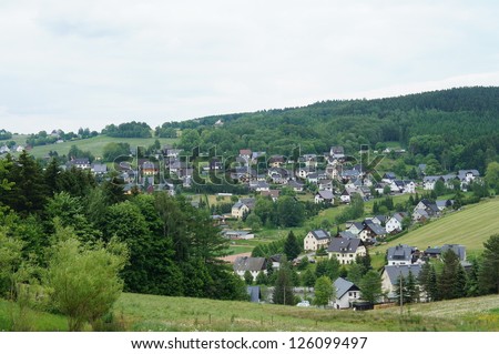 Idyllic village in the Ore Mountains in Saxony, Germany, houses with slate roofs, surrounded by pastures, green forests and rolling hills/Village in the Erzgebirge, Germany