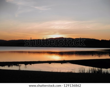 Evening atmosphere over a lake, in the background a hill chain/Evening mood over a lake