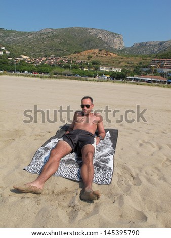 Man sunbathing on the beach of Castelldefels