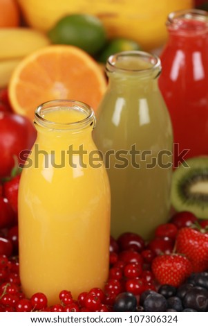 Bottles of different kinds of smoothies surrounded by fresh fruits