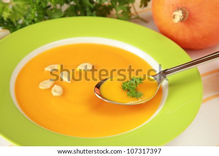 Plate with pumpkin soup and a pumpkin in the background