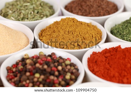 Various exotic spices in white bowls. Selective focus on the curry powder.