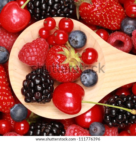 Cherries, strawberries, bilberries, red currants, raspberries and blackberries on a wooden spoon