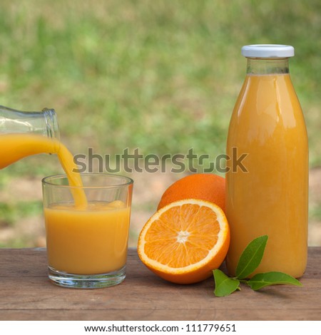 Fresh orange juice is being molded from a bottle into a glass