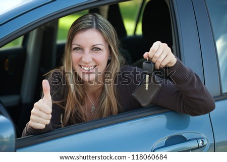 A happy driver leaning out of the window and showing the car key