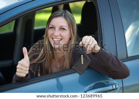 A smiling woman is leaning out of the window and showing a key