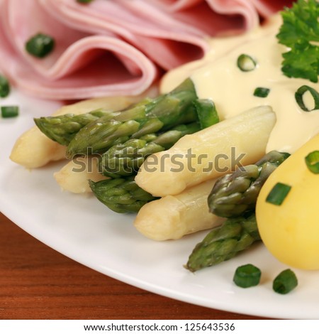 Cooked Asparagus served with potatoes, ham and hollandaise sauce