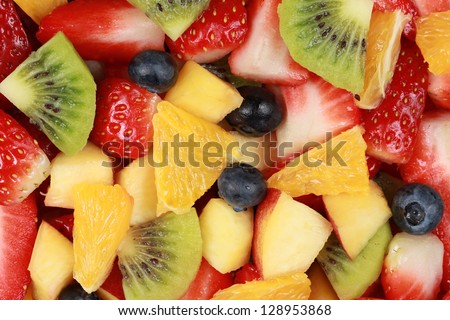Top view of a fruit salad with strawberries, oranges, kiwi, blueberries and peaches
