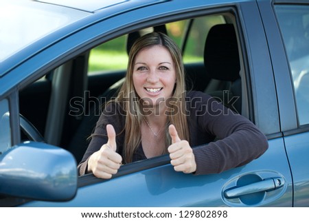 A successful driver looking out of the window and showing thumbs up