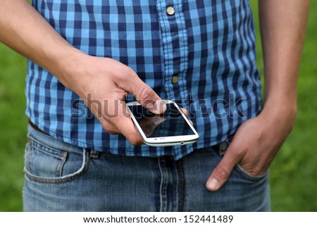 A young man is using a smartphone by tipping with his fingers