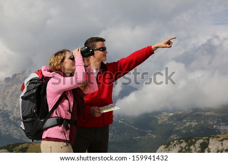 Young woman searching the destination while her boyfriend is showing the direction in the mountains