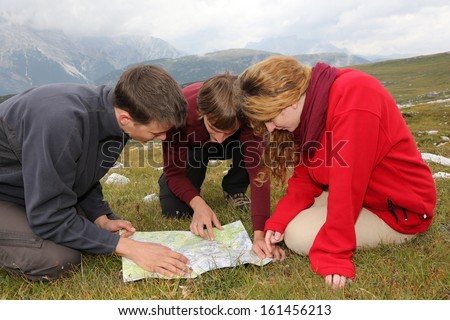 Group of young people are searching the destination on a map in the mountains