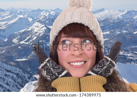 Portrait of a happy woman in winter with gloves and cap in the mountains