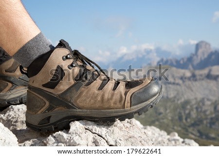 Hiking boots of a hiker on a rock with mountains landscape in the background