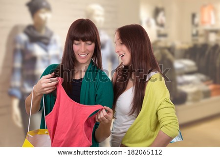 Young women with shopping bags buying clothes in clothing store