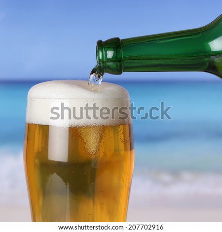 Beer pouring from a bottle into a glass on the beach and the sea