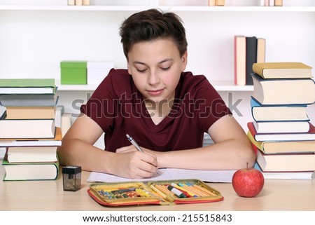 Young boy writing his homework at school in an exercise book