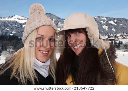 Two smiling women with warm clothing on winter holidays in the mountains