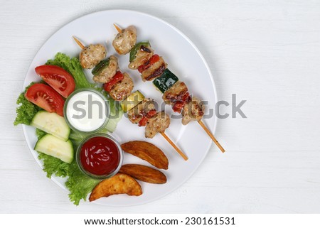 Chicken meat skewers meal with potatoes, vegetables and lettuce on a plate from above