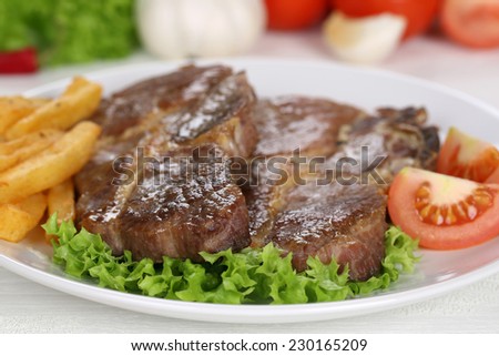 Pork chops steaks cutlet meal with fries, vegetables and lettuce on plate