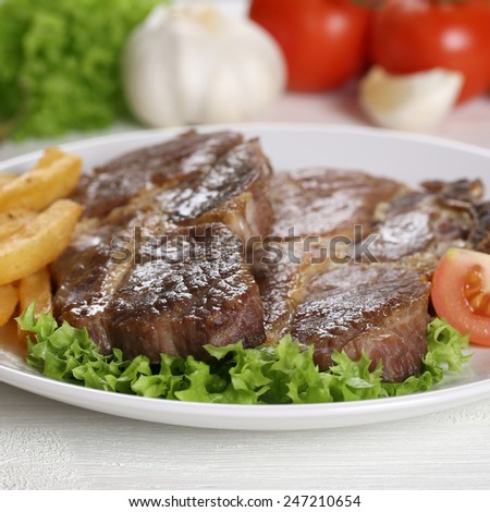 Pork chops steaks meat meal with fries and salad on plate