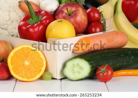 Fruits and vegetables like oranges, apple, tomatoes, banana in wooden box