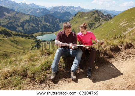 Male and female hikers in the German Alps near Oberstdorf reading a map for orientation.