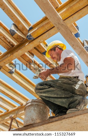 Smiling authentic construction builder working with clamps underneath slab formwork beams