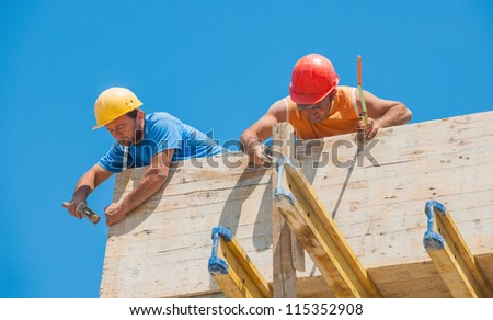 Authentic construction builders working together for nailing wooden cement formwork in place