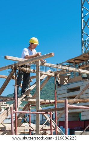 Construction worker on scaffold busy with guiding strings