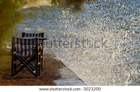 Image shows an empty table and chairs on a berth hit by rough sea waves