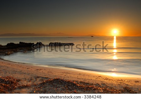Image shows the sun rising over a mediterranean beach