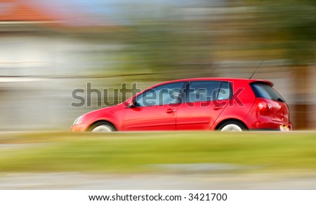 stock photo Panning shot of a fast moving red small car