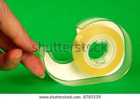 Image shows female fingers pulling a piece of sticky tape from a plastic dispenser
