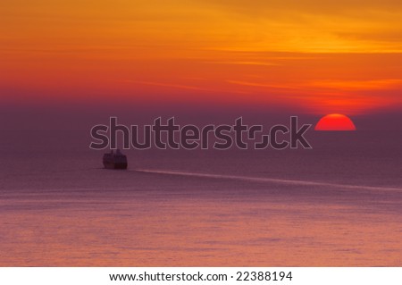 Cruise ship traveling towards the open sea as the sun sets over the Mediterranean