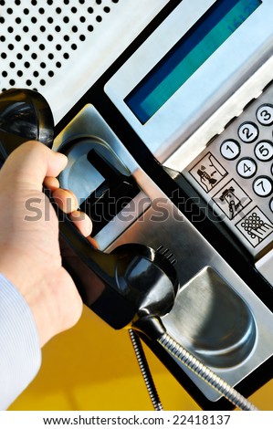 Picture of a male hand retrieving the handset of a public telephone in order to make a call