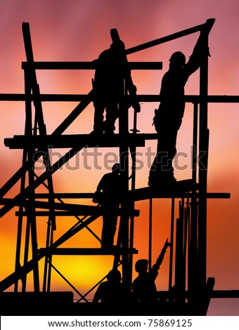 Silhouette of construction workers on scaffold working against a vivid and colorful sunset