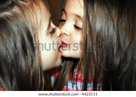 Two beautiful sisters kissing and looking at each other.